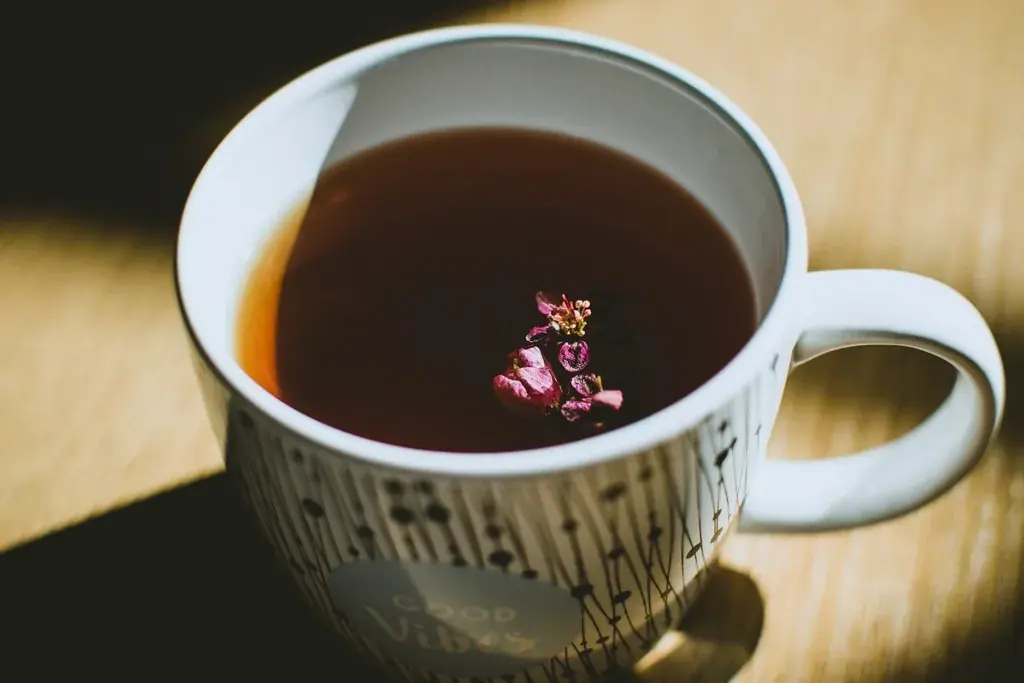 Tisane rouge dans une tasse blanche, une fleur séchée posée à la surface